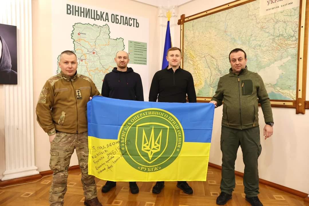 на фото Начальник ОВА Сергій Борзов та троє чоловіків тримають Прапор України