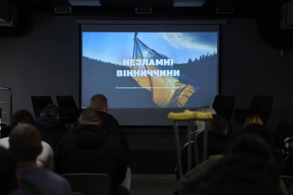 Люди у приміщенні перед екраном