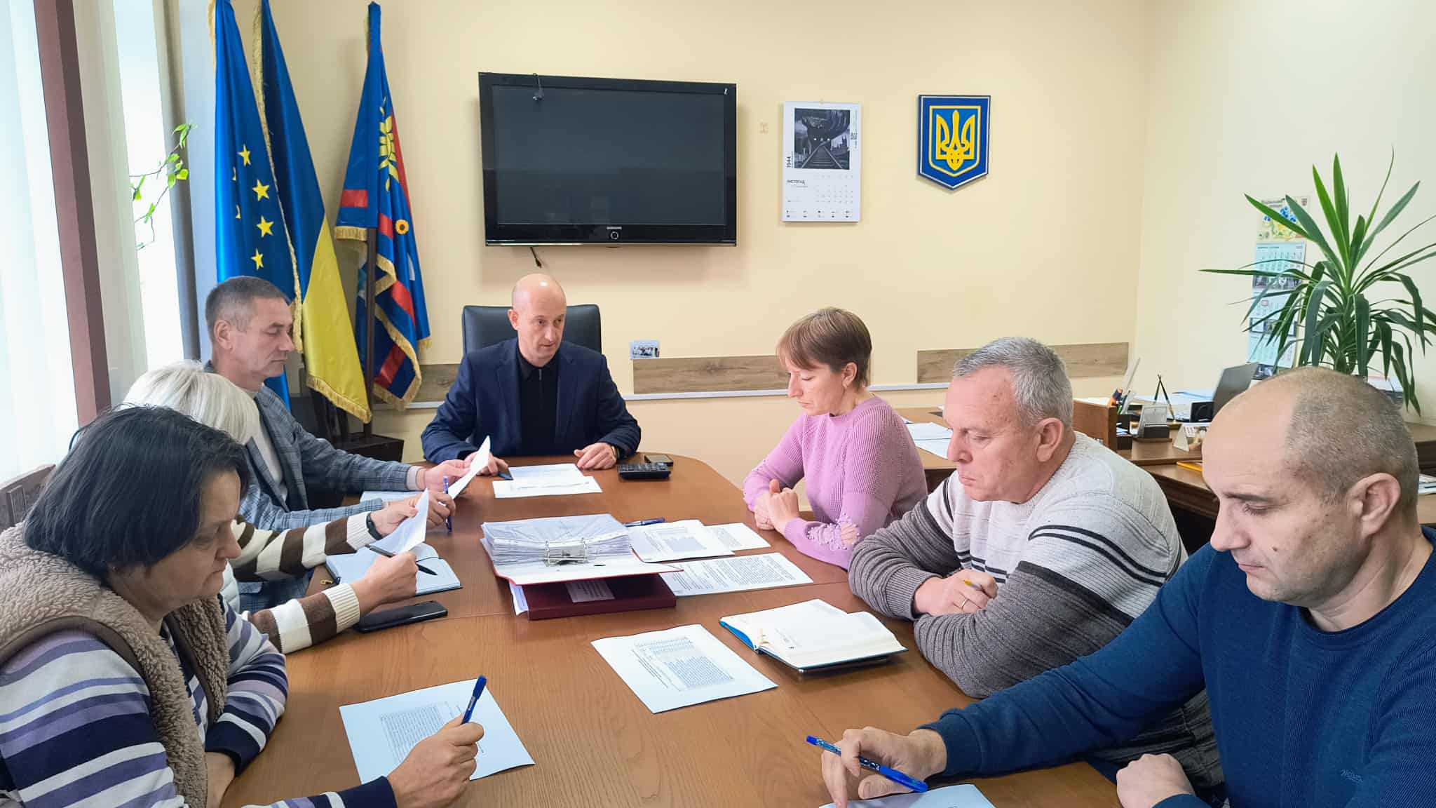 В кабінеті за робочим  столом сидят члени Комісії, перед ними документи та записники