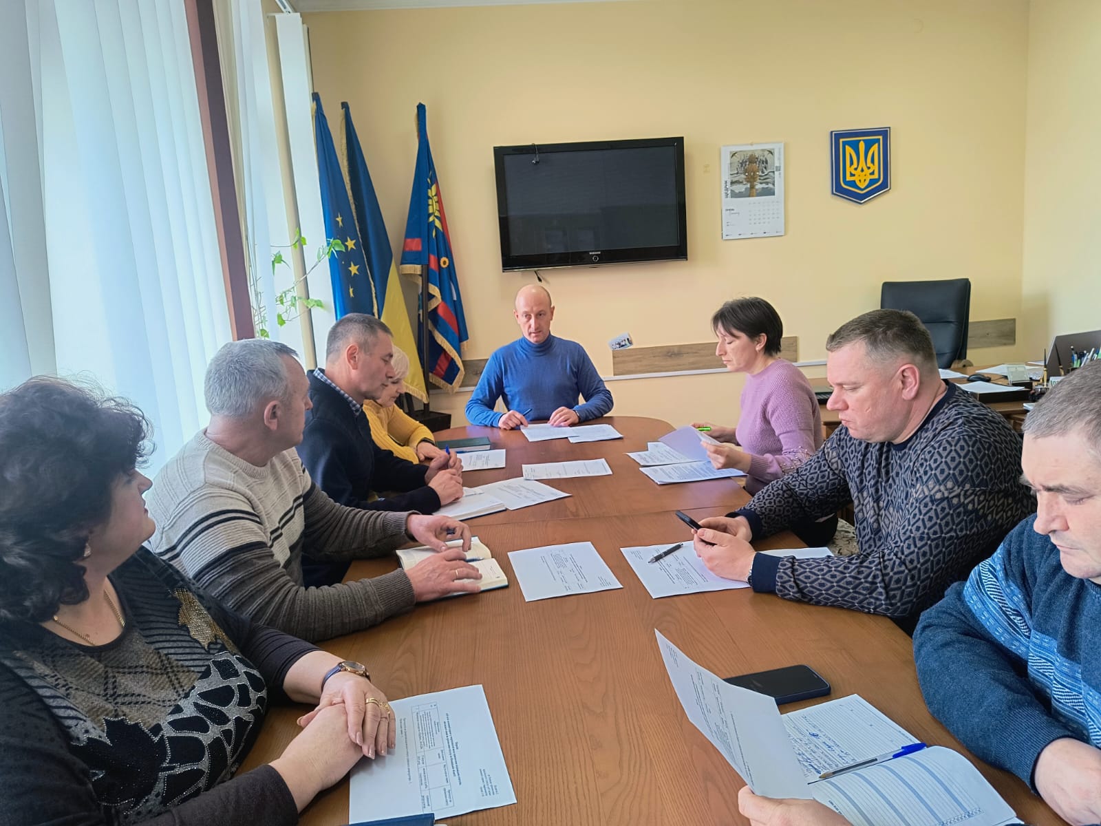 Директор Департаменту Олег Сідоров та інші учасники  комісії  в кабінеті  сидят за круглим столом перед ними лежать документи