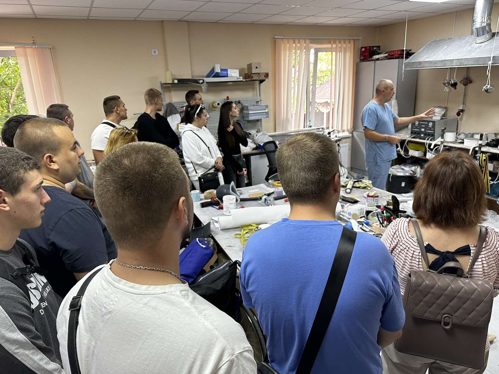 Доповідач веде жваву бесіду (або дискусію) з групою з десяти осіб, які стоять, утворивши півколо