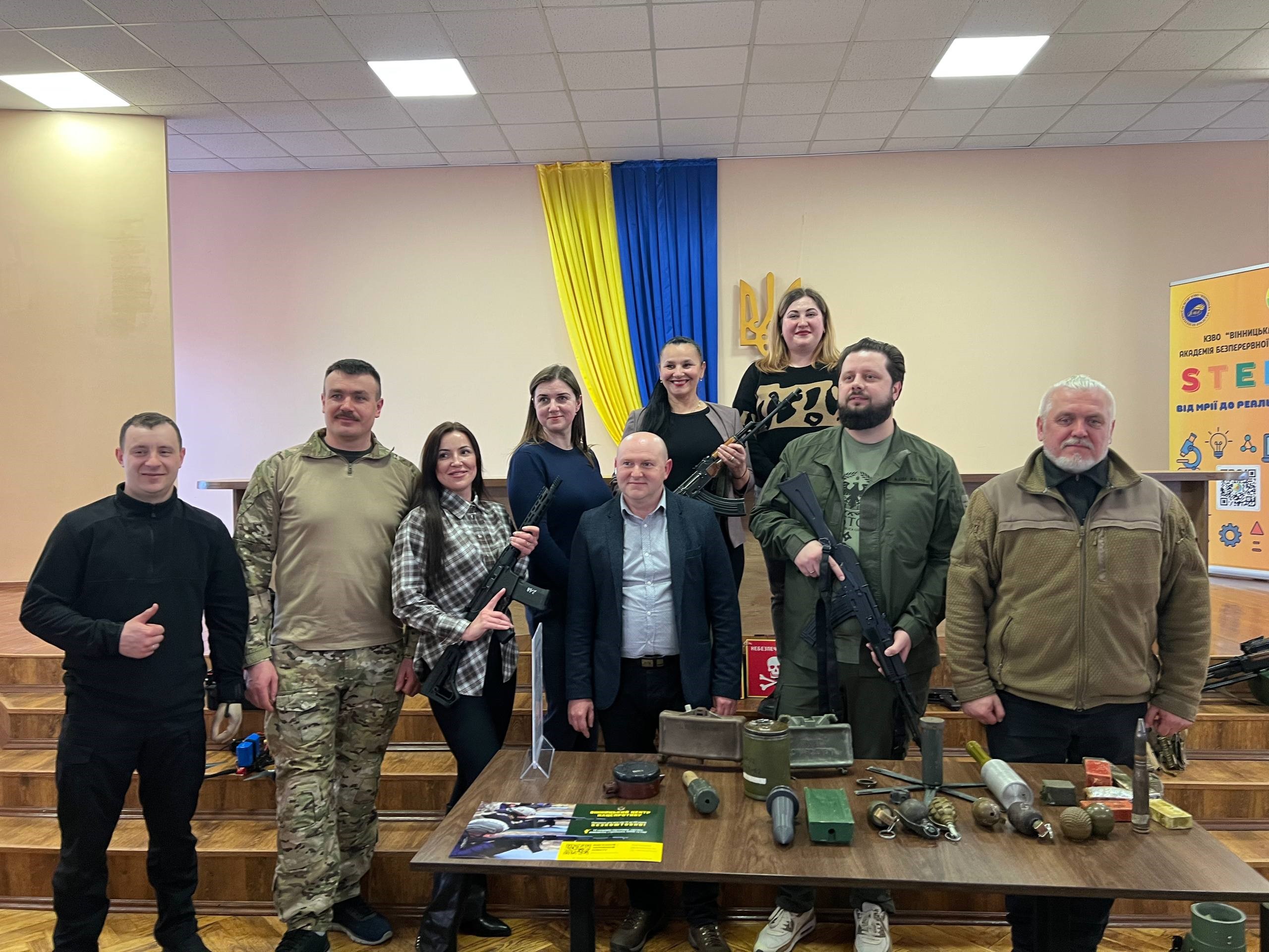 Дев'ятеро людей стоять навколо столу зі зброєю та іншими предметами