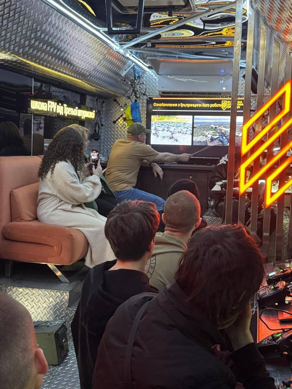 Інструктор в спеціально обладнаному для навчання по користуванню FPV-дронами автобусі показує цивільним на моніторі інформацію по користуванню