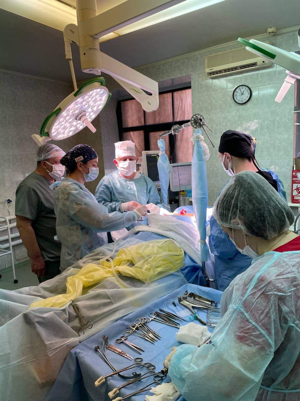 Група медичних фахівців готова провести операцію, на фото видно операційну залу.