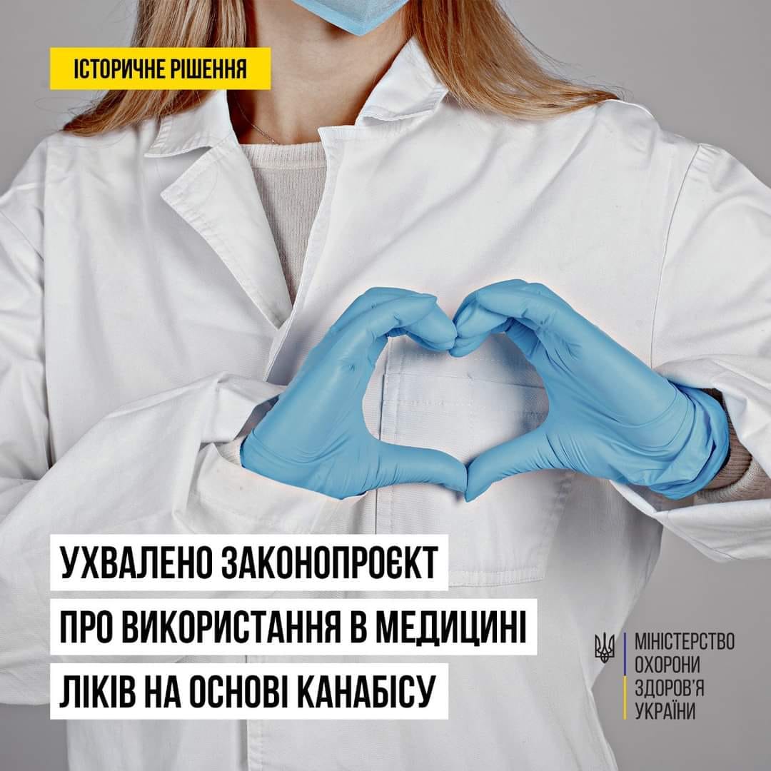 Жінка в білому халаті та синіх рукавичках робить серцеву форму.