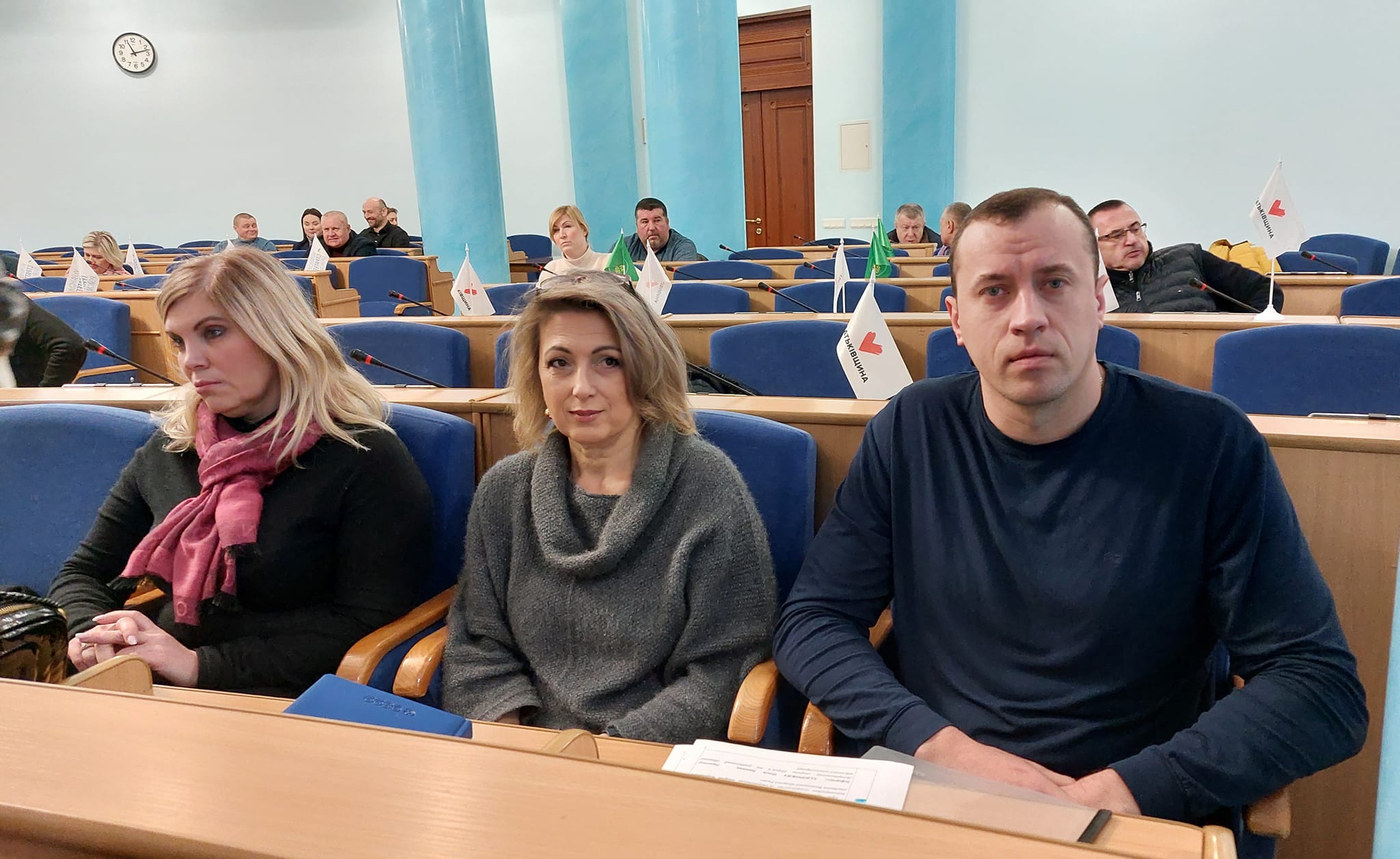Група людей сидить у залі.