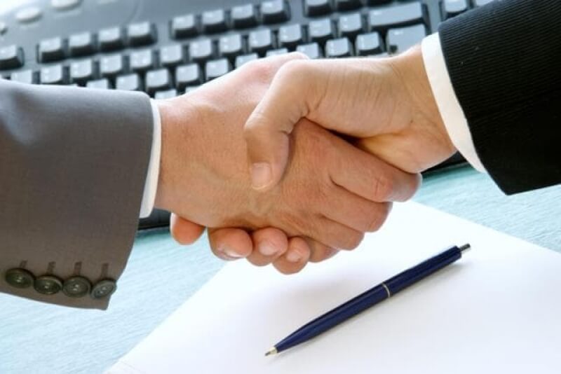 Два бізнесмена потискають руки над папером