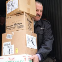 Чоловік тримає в руках чотири коробки з гуманітарною допомогою