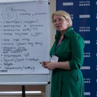 Учасниця заходу стоїть біля фліпчарту