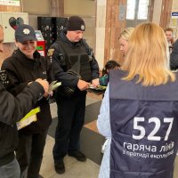 Учасники інформаційної кампанії «ПРИДИВИСЬ» в приміщенні залізничного вокзалу міста Вінниці. Жінки вдягнені в жилети з надписоа "Україна без торгівлі людьми"