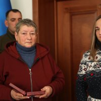 на фото двоє жінок, одна з яких тримає в руках нагороду