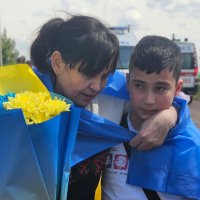 Жінка і хлопчик з прапором України та квітами