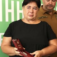 Жінка тримає у руках нагороду
