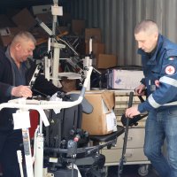 Двоє чоловіків вивозять з вантажного автомобіля медичне обладнання