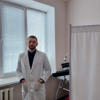 Чоловік у лабораторному халаті перед білою заслінкою