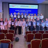 Люди фотографуються на сцені зі складеними буквами Вінниччина без торгівлі людьми 