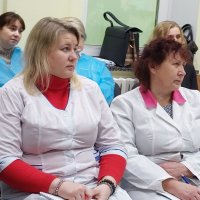 Група жінок у білих халатах сидить у кабінеті