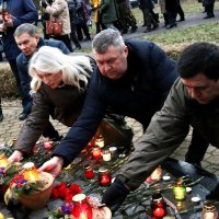 Чоловіки та жінка покаладають ламападки біля статуї 