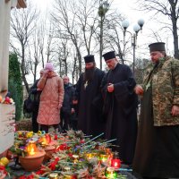 Чоловіки та жінки перед статуєю на покладанні