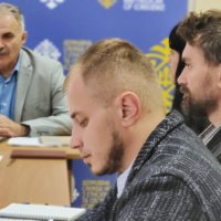 Чоловіки в залі за столом проводять нараду 