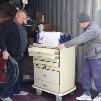 Двоє чоловіків вивозять з вантажного автомобіля тумбочку
