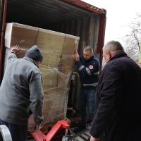 Троє чоловіків розвантажують гуманітарний вантаж